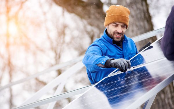 Bildaufnahme Mann mit Kappe der eine Solaranlage installiert.